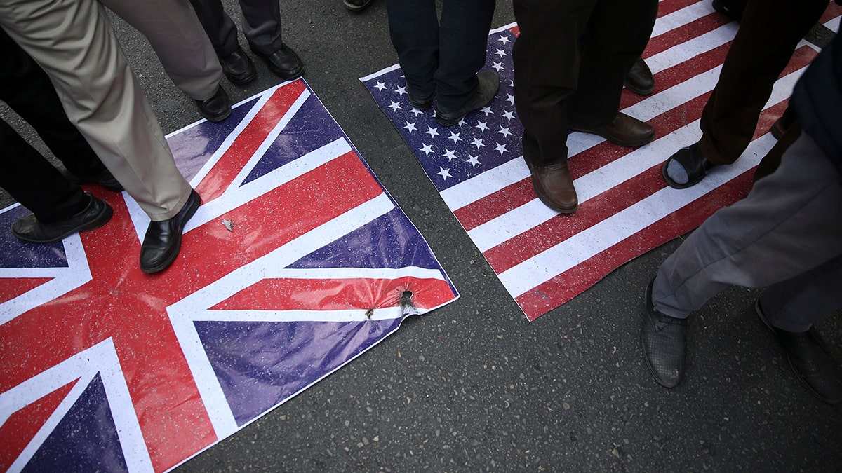 Representations of the U.S. and British flags are walked on by demonstrators during an annual rally in front of the former U.S. Embassy in Tehran, Iran, on Sunday, Nov. 4, 2018.