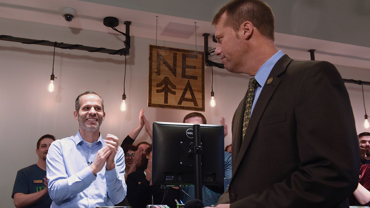 NETA co-founder Arnon Vered sells Northampton Mayor David Narkewicz, right, the first legal recreational sale of marijuana, an edible marijuana candy bar, at the NETA facility on Tuesday, Nov. 20, 2018, in Northampton, Mass.