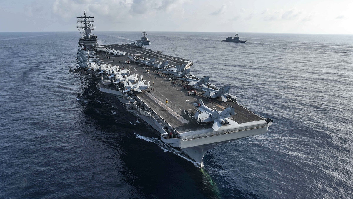 The aircraft carrier USS Ronald Reagan and the guided-missile destroyer USS Milius, center, conduct a photo exercise with Japan Maritime Self-Defense Force ships. (U.S. Navy)