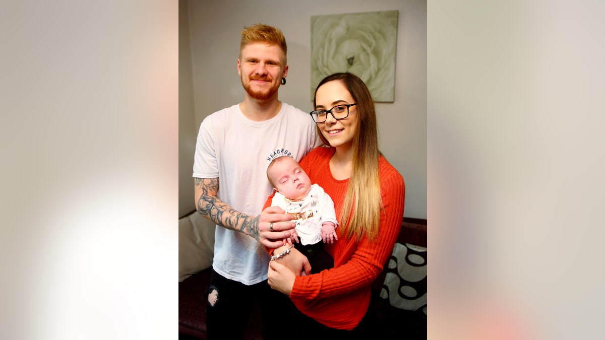 Georgia Axford, 19, and Tyler Kelly, 21, with baby Piper-Kohl, who underwent a pioneering spine surgery while still in her mother's womb.
