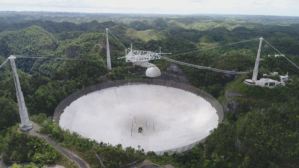 In this recent view of the Arecibo Observatory in Puerto Rico, the 96-foot line-feed antenna that once dangled above the telescope dish is still missing. It broke off during Hurricane Maria and punctured the dish below.