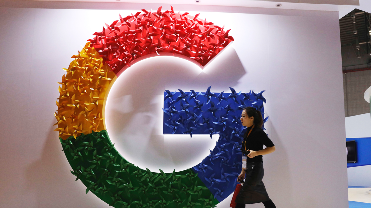 In this Monday, Nov. 5, 2018, photo, a woman carries a fire extinguisher past the logo for Google at the China International Import Expo in Shanghai. (AP Photo/Ng Han Guan)