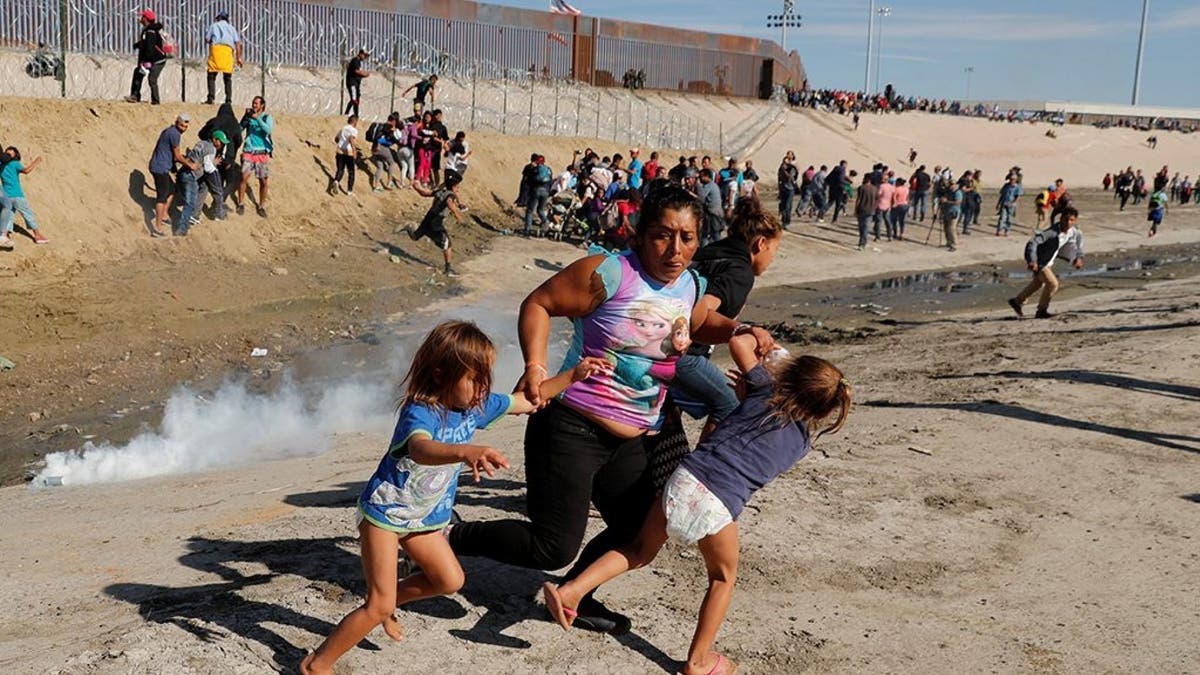 A migrant family, part of a caravan of thousands traveling from Central America en route to the United States, running away from tear gas in front of the border wall between the U.S and Mexico in Tijuana on Sunday.