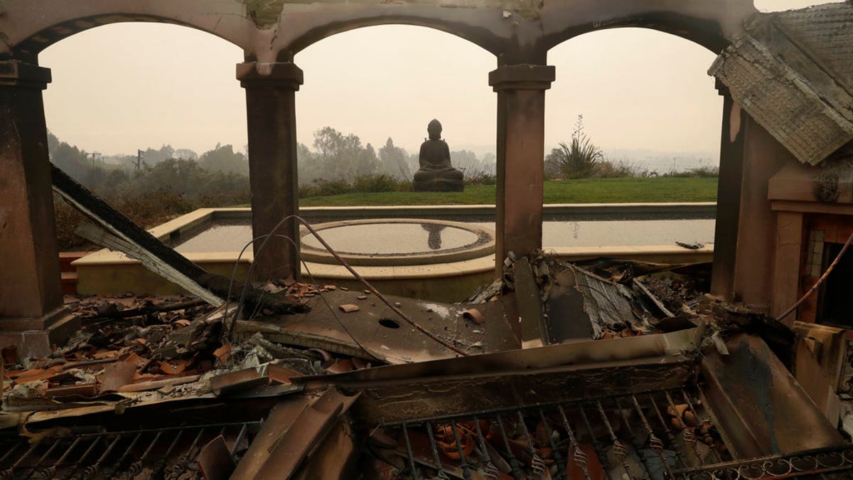 A Buddha statue stands among the damage caused by a wildfire at a home in Malibu, Calif.