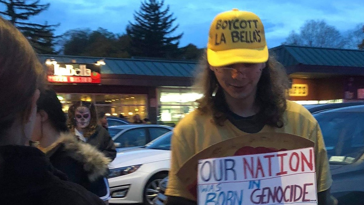 Protesters stand in front of La Bella Pizza Bistro to boycott the shop's American flag mural.