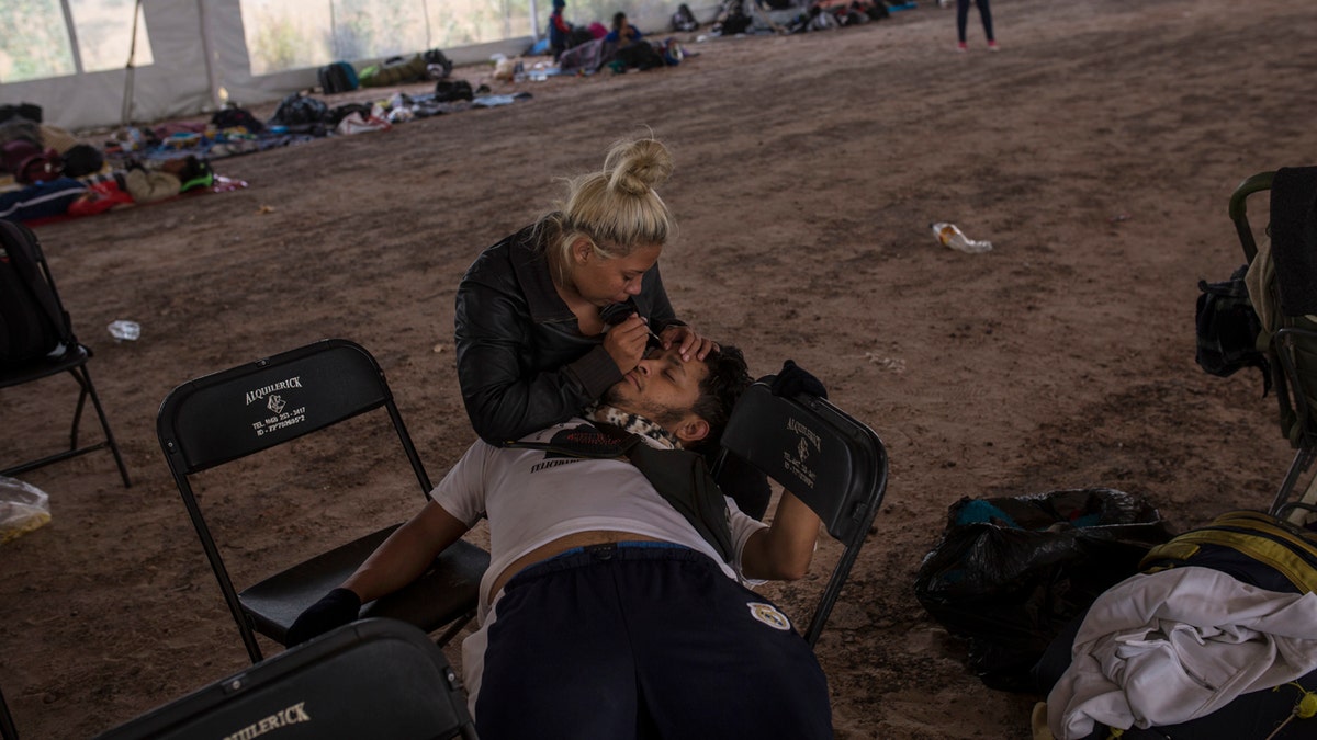 Central American migrant Jenifer Argueta plucks the eyebrows of Honduran Kevin Banegas, while waiting to receive donated food in Palmillas, Mexico, Saturday, Nov. 10, 2018.