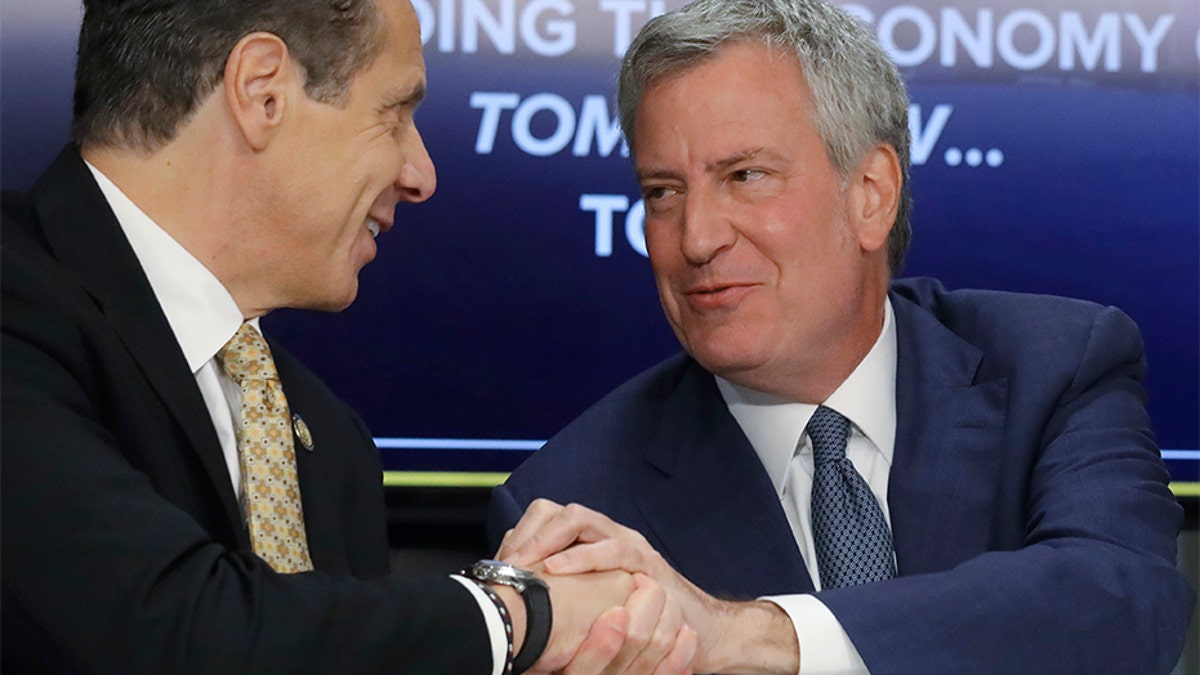 New York Gov. Andrew Cuomo, left, and New York City Mayor Bill de Blasio shake hands during a news conference Tuesday announcing the Amazon deal. Members of their own party are now criticizing the incentives package being offered to Amazon.
