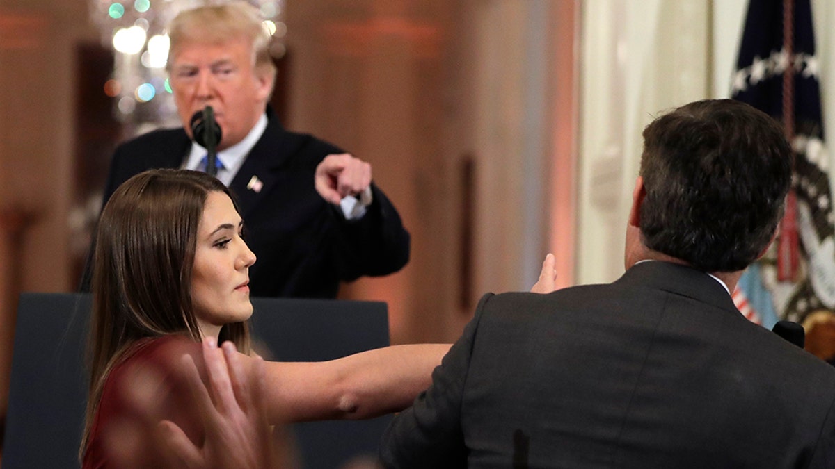 As President Donald Trump points to CNN's Jim Acosta, a White House aide tries to take the microphone from him during a news conference in the East Room of the White House, Wednesday, Nov. 7, 2018, in Washington. (AP Photo/Evan Vucci)