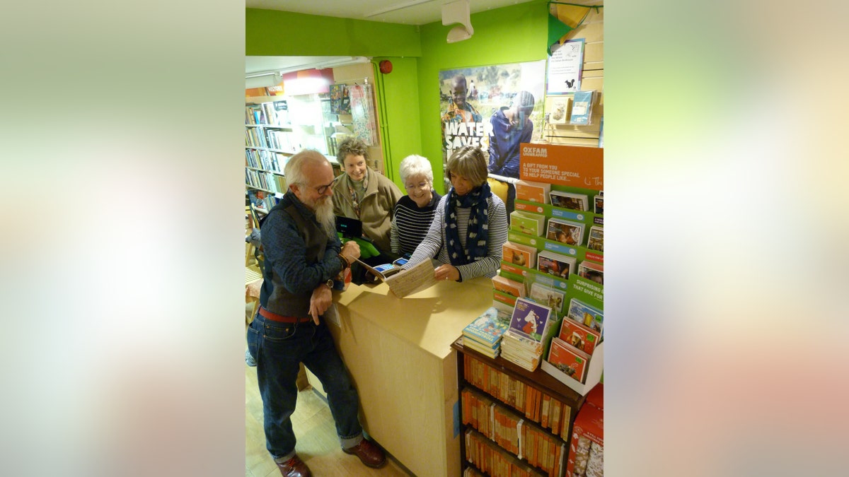 Oxfam shop manager Tony Cooper, who spotted the first edition The Hobbit, with staff at the shop where the book was discovered. (Credit: SWNS)