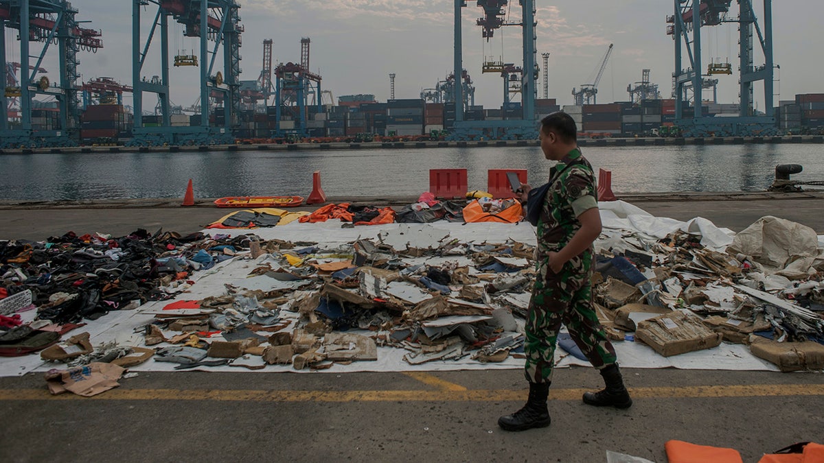 An Indonesian soldiers walk past debris retrieved from the waters where Lion Air flight JT 610 is believed to have crashed at Tanjung Priok Port in Jakarta, Indonesia, Wednesday, Oct. 31, 2018.