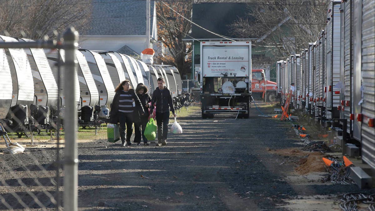 In this Wednesday, Nov. 14, 2018 photo Sonia Geha, left, and her mother Laila Eid, second from left, both of Lawrence, Mass., carry belongings as they depart a trailer camp for people displaced by gas line failures and explosions on Sept. 13, 2018.