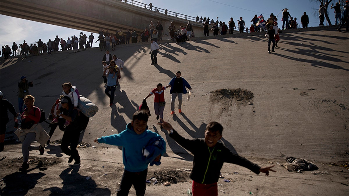 Migrants cross the river at the Mexico-U.S. border after pushing past a line of Mexican police at the Chaparral crossing in Tijuana, Mexico, on Sunday.
