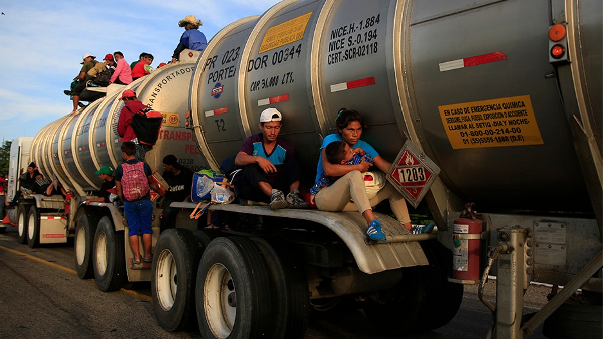 A woman holding her baby hitches a ride on the fender of a tanker in Niltepec, Mexico, on Tuesday.