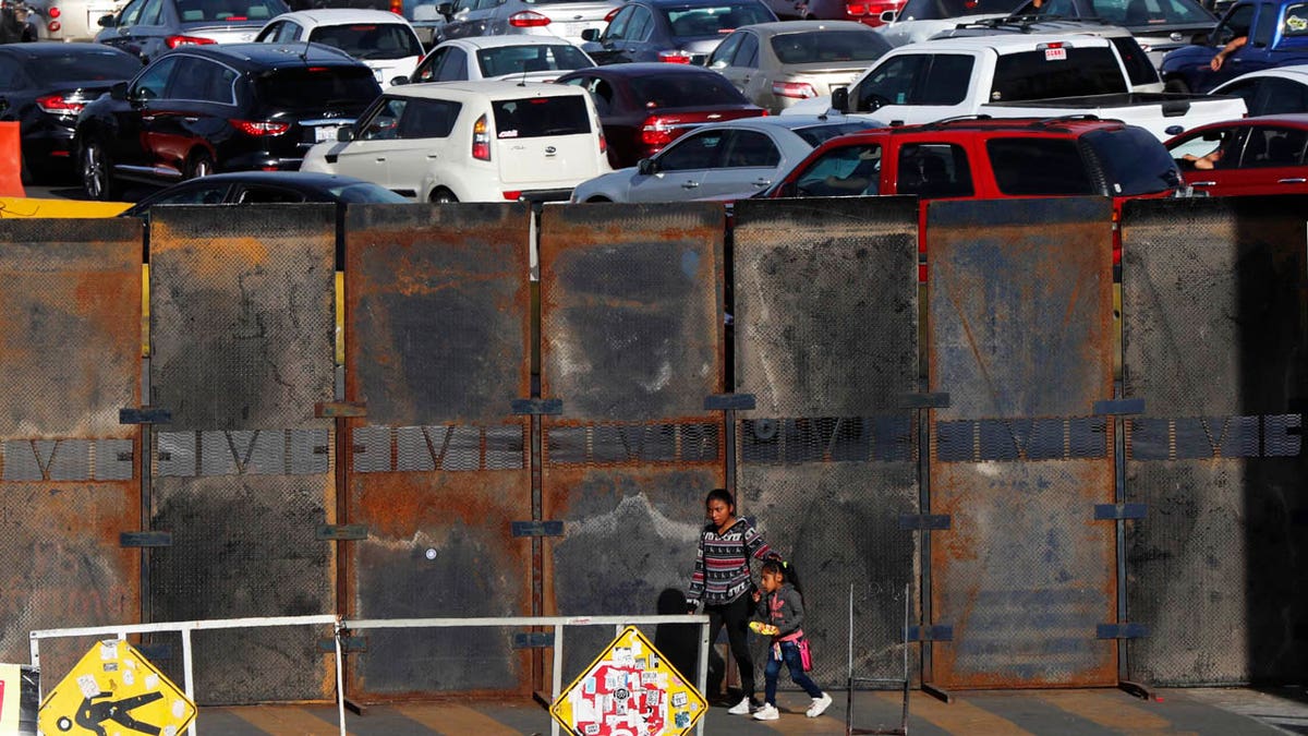 A newly erected barrier wall stands amid cars at the Mexico-U.S. border, as they wait in line to enter the U.S., as they leave Tijuana, Mexico, Monday, Nov. 19, 2018.