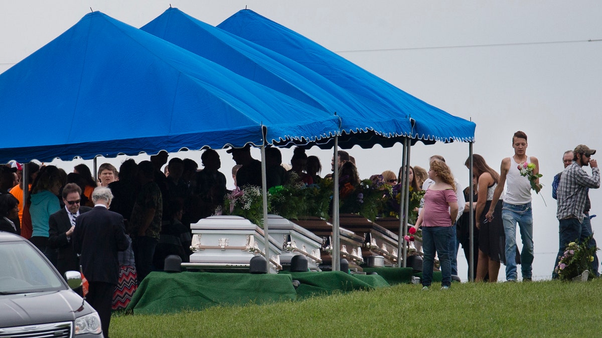 In this May 3, 2016, file photo, mourners gather around caskets for six of the eight members of the Rhoden family found shot April 22, 2016, at four properties near Piketon, Ohio.