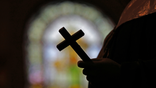 FILE - This Dec. 1, 2012 file photo shows a silhouette of a crucifix and a stained glass window inside a Catholic Church in New Orleans. As U.S. Catholic bishops gather for an important national assembly, the clergy sex abuse crisis dominates their agenda. But it's only one of several daunting challenges facing the nation's largest religious denomination. While federal and state law enforcement agencies widen their investigations of abuse, the church finds itself with ever fewer priests and nuns in service. (AP Photo/Gerald Herbert)