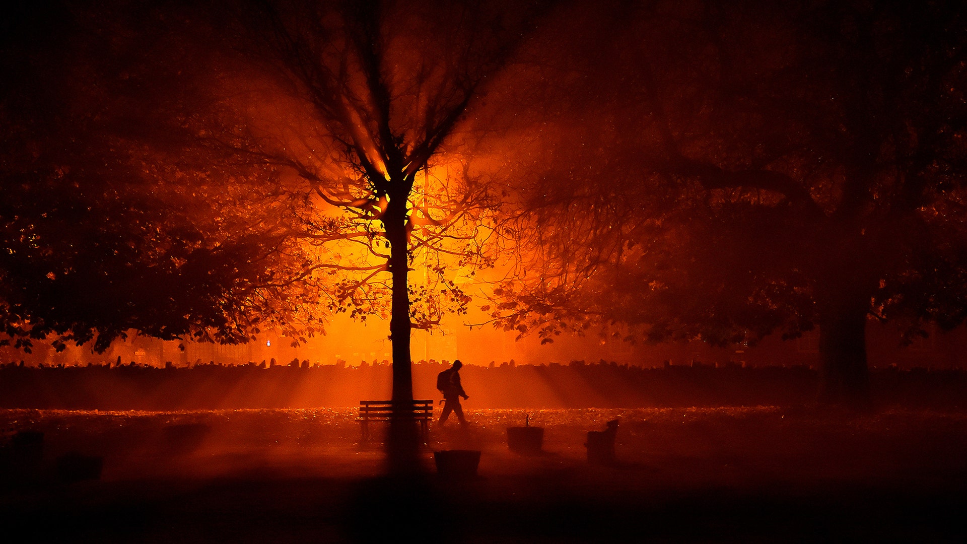 A man walks through a park during cold fog at night in Athboy, Ireland, Oct. 31, 2018. 