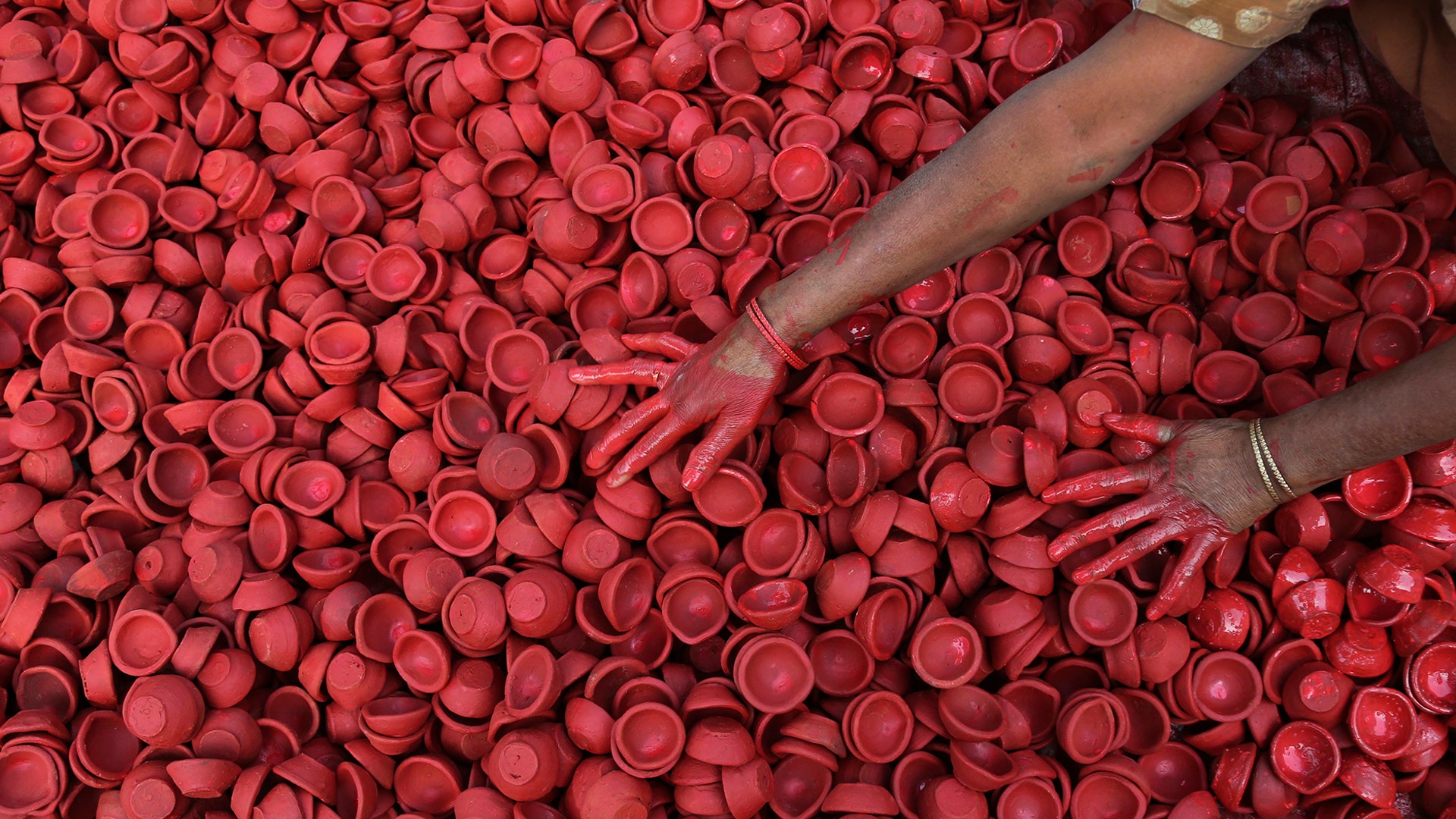 An Indian woman colors earthen lamps ahead of the Diwali festival in Jammu, Oct. 30, 2018.