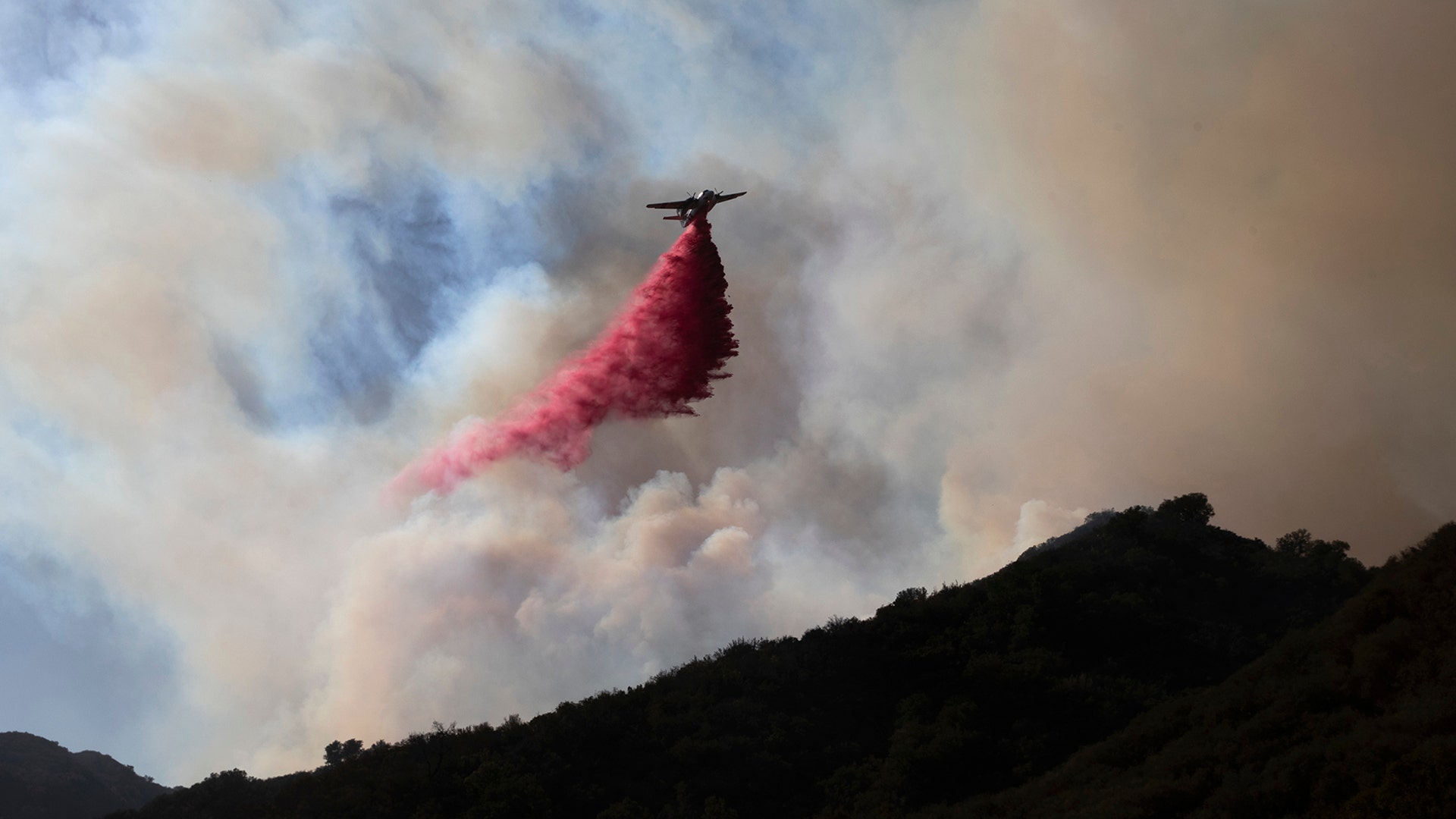A plane drops fire retardant on a burning hillside in Malibu, California, November 11, 2018.