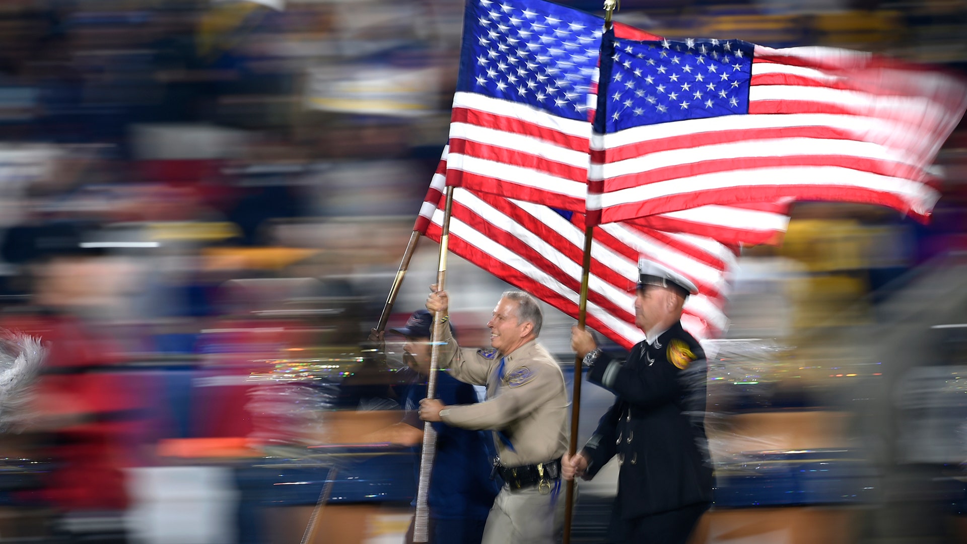 Fire and law enforcement first responders run with United States flags as they lead players out of the tunnel before an NFL football game between the Los Angeles Rams and the Kansas City Chiefs, in Los Angeles, Nov. 19, 2018. 