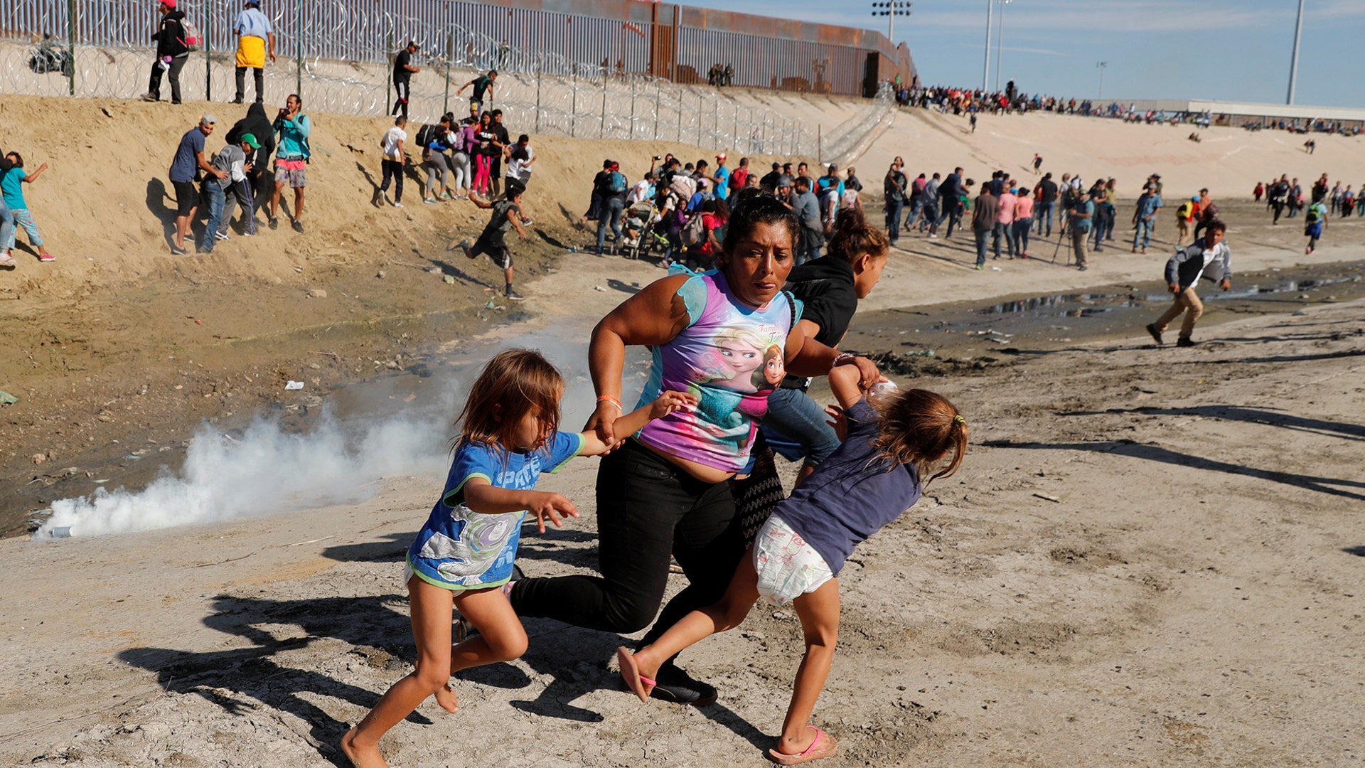 A migrant family, part of a caravan of thousands traveling from Central America en route to the United States, run away from tear gas in front of the border wall between the U.S. and Mexico in Tijuana, Mexico, November 25, 2018. 