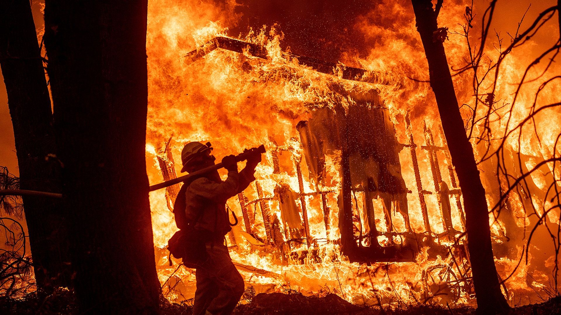 Firefighter Jose Corona sprays water as flames from the Camp Fire consumed a home in Magalia, California November 9, 2018.