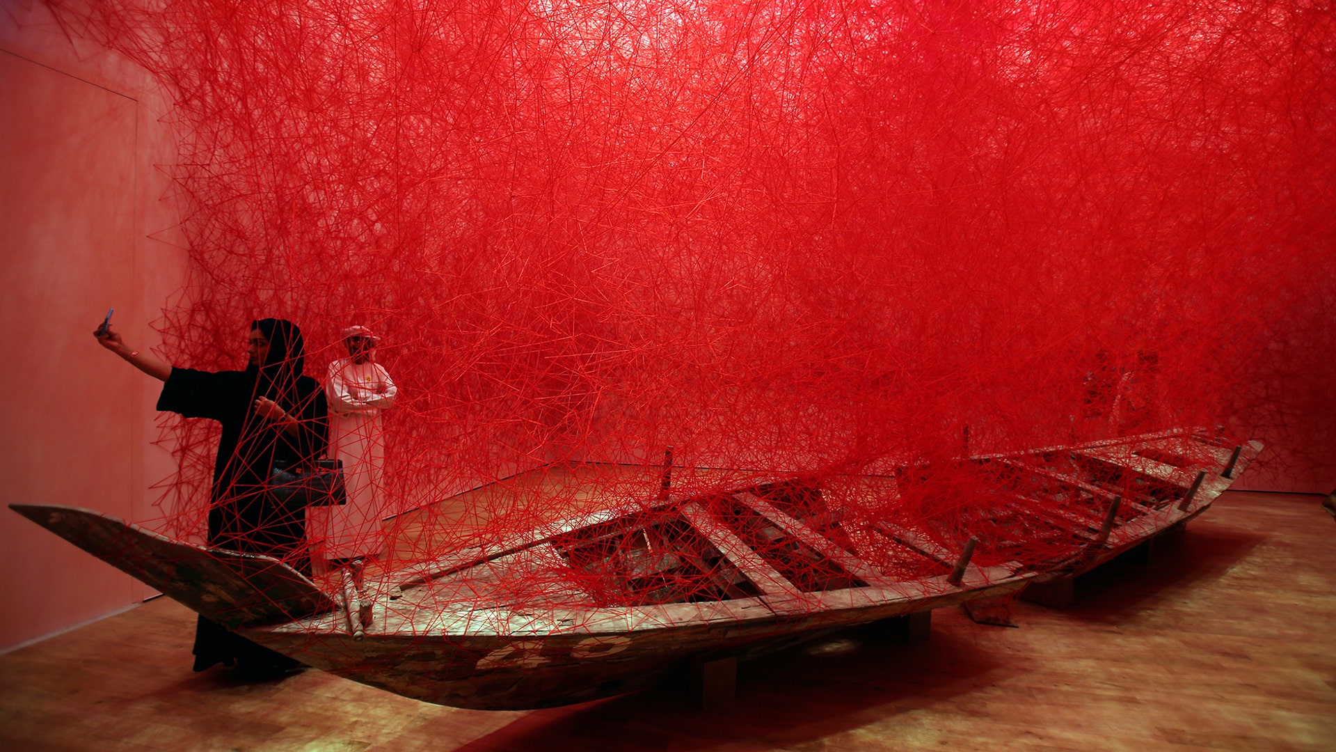 A woman takes a selfie with the "Departure" installation by Japanese artist Chiharu Shiota during the launch of the Jameel Arts Centre in Dubai, United Arab Emirates, November 11, 2018. 