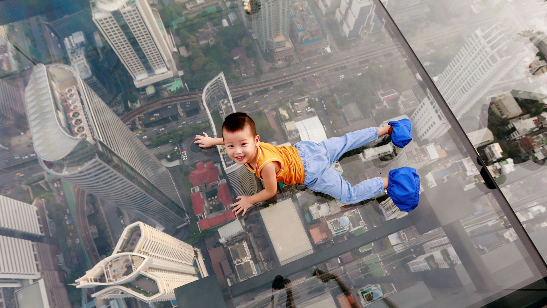 A boy plays on the glass floor at Thailand's first skywalk in Bangkok, Thailand, Nov. 18, 2018. 