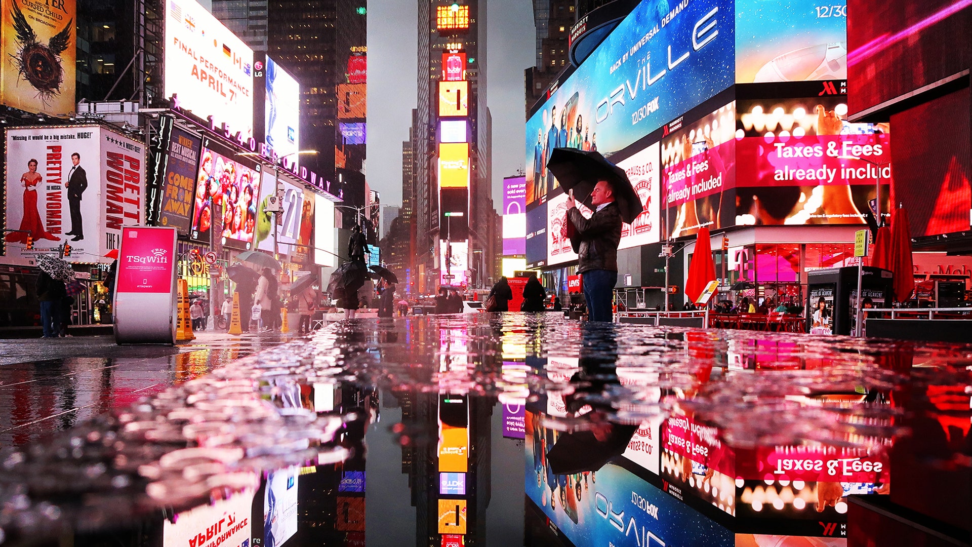 A man takes a picture during a rainstorm in Times Square in New York City, Nov. 26, 2018