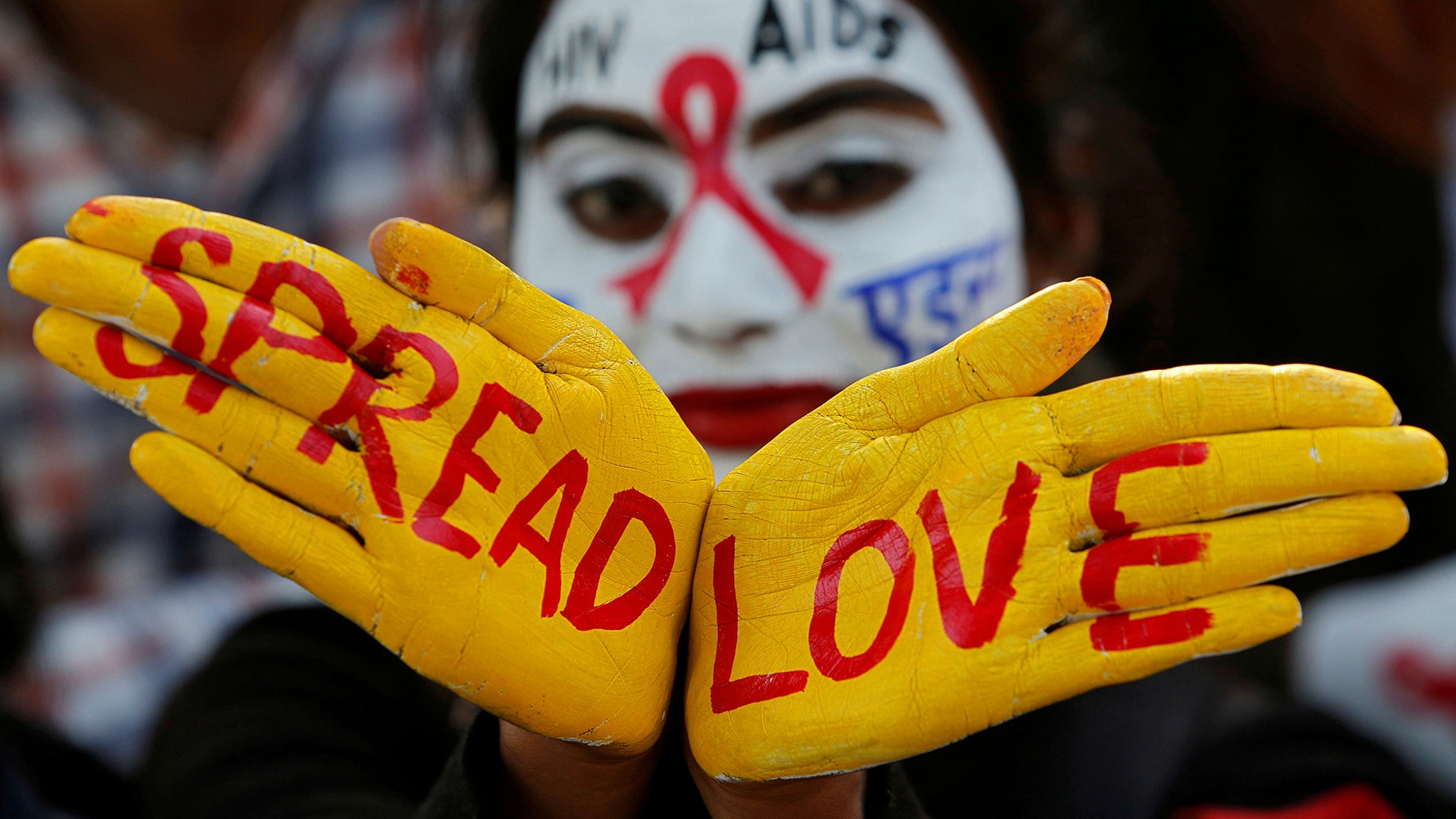 A student poses as she displays her face and hands painted with messages during an HIV/AIDS awareness campaign on the eve of World AIDS Day in Chandigarh, India, Nov. 30, 2018. 
