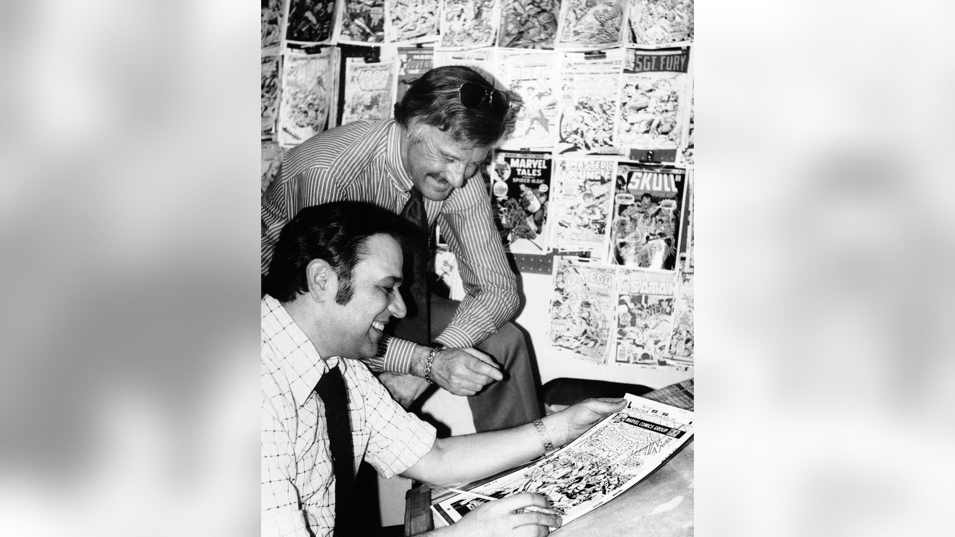 FILE - In this Jan. 10, 1976, file photo, Stan Lee, standing, publisher of Marvel Comics, discusses a "Spiderman" comic book cover with artist John Romita at Marvel headquarters in New York. In 1972, Lee became Marvel's publisher and editorial director; four years later, 72 million copies of Spider-Man were sold.