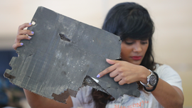 Families show debris, ask search for Malaysia jet to resume