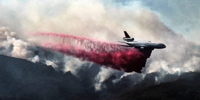 A firefighting DC-10 makes a fire retardant drop over a wildfire in the mountains near Malibu Canyon Road in Malibu, Calif. on Sunday, Nov. 11, 2018. Strong Santa Ana winds have returned to Southern California, fanning a huge wildfire that has scorched a string of communities west of Los Angeles. A one-day lull in the dry, northeasterly winds ended Sunday morning and authorities warn that the gusts will continue through Tuesday. (AP Photo/Richard Vogel)