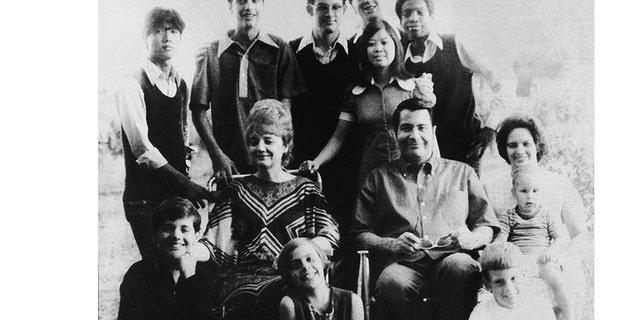 Portrait of Jim Jones and his wife, Marceline Jones seated in front of their adopted children and next to his sister-in-law (right) with her three children, California, 1976.