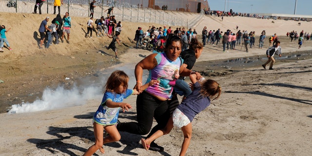 A migrant family, part of a caravan of thousands traveling from Central America en route to the United States, run away from tear gas in front of the border wall between the U.S. and Mexico in Tijuana, Mexico November 25, 2018. REUTERS/Kim Kyung