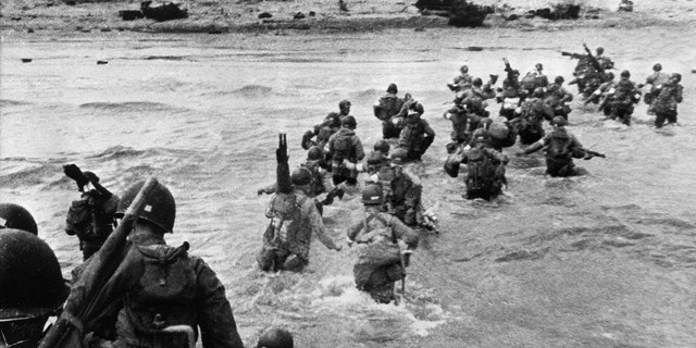 File photo - American troops supporting those already on the coast of Northern France, plunge into the surf and wade shoreward carrying equipment, on Utah Beach, Les Dunes de Madeleine, France.