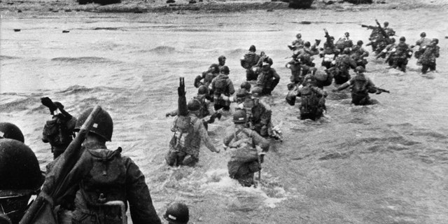File photo - American troops supporting those already on the coast of Northern France, plunge into the surf and wade shoreward carrying equipment, on Utah Beach, Les Dunes de Madeleine, France.
