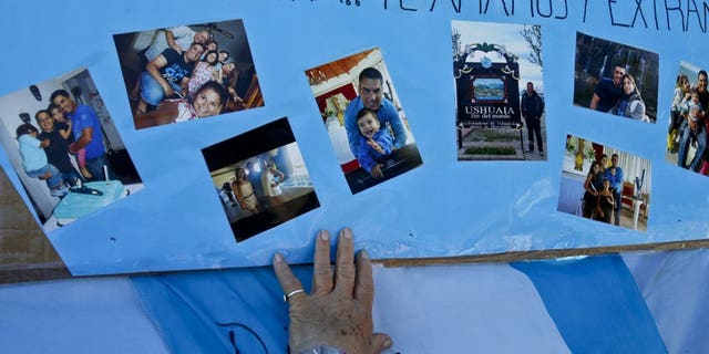 A woman touches a poster, overlaid with snapshots of Celso Oscar Vallejo, one of the crew members of the missing ARA San Juan, that hangs on a fence enclosing the Mar del Plata Naval Base, in Argentina, Thursday, Nov. 23, 2017.