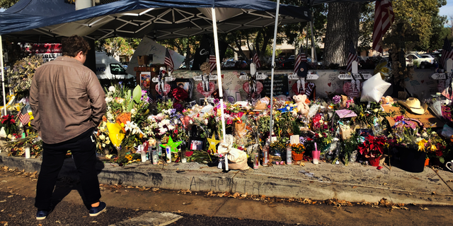 A passerby stops to look over a street side memorial to the shooting victims of the Borderline Bar in Thousand Oaks, Calif. on Tuesday, Nov. 27, 2018. (G3 Box News Photo/Amanda Lee Myers)
