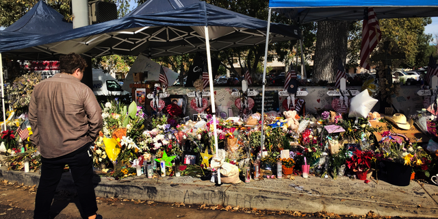 A passerby stops to look over a street side memorial to the shooting victims of the Borderline Bar in Thousand Oaks, Calif. on Tuesday, Nov. 27, 2018. (AP Photo/Amanda Lee Myers)