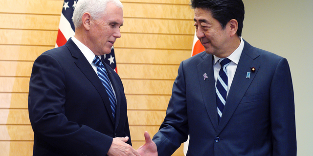 U.S. Vice President Mike Pence, left, and Japanese Prime Minister Shinzo Abe shake hands at Abe's official residence in Tokyo Tuesday, Nov. 13, 2018. (AP Photo/Eugene Hoshiko)