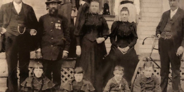 Maker would often write home to his family during World War I. He is pictured here as a young boy, on the far right of the bottom row. To his side, from right to left, are his stepsister Harriet, sister Eva and brother Clifford (Kip). His uncle Edward, wearing a Union Army uniform, is second from the left in the middle row, next to Edward's brother, Andrew. Both of those men fought for 19th Maine Regiment during the Civil War. Maker's father, Winfield, is standing in front of the bicycle on the far right.