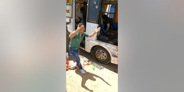 A man screams beside a bus carrying Coptic Christians which came under attack outside Cairo, Friday, Nov. 2, 2018. Islamic militants on Friday ambushed a bus carrying Christian pilgrims on their way to a remote desert monastery south of the Egyptian capital, killing at least seven and wounding a dozen more, the Interior Ministry said. (Egypt’s Coptic Orthodox Church via AP)