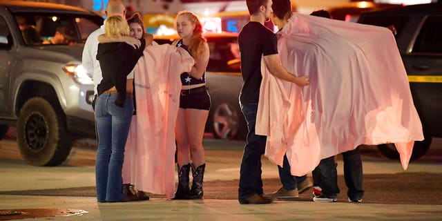 People comfort each other as they stand near the scene of a mass shooting in Thousand Oaks, Calif., early Thursday morning.