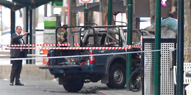 A burnt out vehicle is seen on Bourke Street in Melbourne, Friday, Nov. 9, 2018. A knife-wielding man stabbed two people, one fatally, in Australia's second-largest city last Friday in an attack likely linked to terrorism, police said.