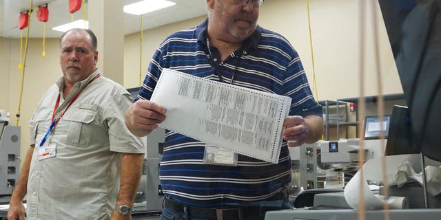 Election workers place ballots into electronic counting machines, Sunday, Nov. 11, 2018, at the Broward Supervisor of Elections office in Lauderhill, Fla. The Florida recount began Sunday morning in Broward County. (Joe Cavaretta/South Florida Sun-Sentinel via AP)