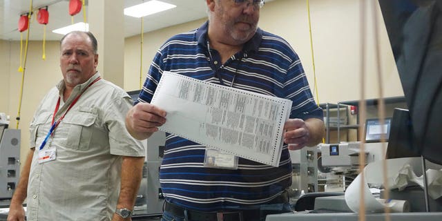 Election workers place ballots into electronic counting machines, Sunday, Nov. 11, 2018, at the Broward Supervisor of Elections office in Lauderhill, Fla. The Florida recount began Sunday morning in Broward County. (Joe Cavaretta/South Florida Sun-Sentinel via AP)