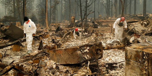 Search and rescue workers search for human remains at a trailer park burned by the Camp Fire, Tuesday, Nov. 13, 2018, in Paradise, California.