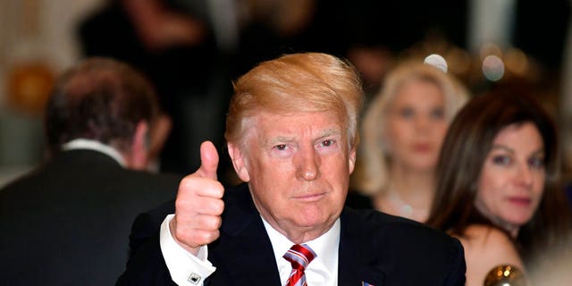 President Donald Trump gives a thumbs-up as he has Thanksgiving Day dinner at his Mar-a-Lago estate in Palm Beach, Fla., Thursday