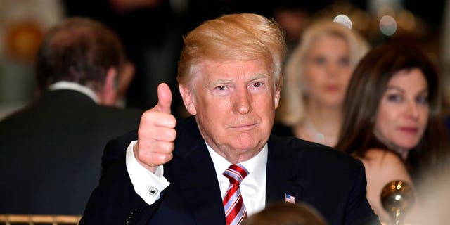 President Donald Trump gives a thumbs-up as he has Thanksgiving Day dinner at his Mar-a-Lago estate in Palm Beach, Fla., Thursday